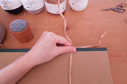 ②糸を1本挟んで、A4ノートに糸を巻きます