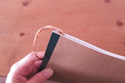 ③糸の端をノートにはさみます