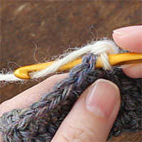 ねじりこま編み[1] 前段の目に針を入れ、糸をかけて引き出します。