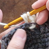 長編み裏引き上げ編み[5] 編み地の裏側に引き出しました。糸をかけ、針先に近い2つのループをくぐらせます。