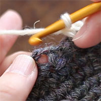 前段の目を束にすくって長編み5目編む[1] 前段のくさり目の下のスペースに針を入れて（くさりを束にすくって）、長編み5目を編んでいきます。