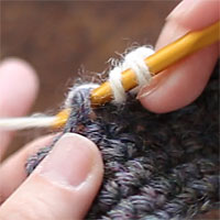 前段の目を束にすくって長編み5目編む[2] 糸をかけ、くさりの下の空間に針を入れました。糸をかけて引き出し、長編みを編みます。