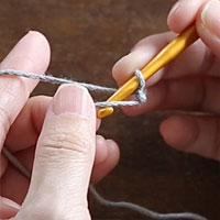 スレッドコードの編み方［4］親指側の糸を、手前から向こうに向かって、針にかけます。